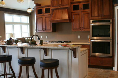 Imagen de cocina tradicional de tamaño medio con armarios con paneles con relieve, electrodomésticos de acero inoxidable y una isla