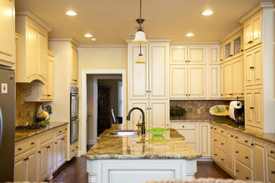 L-shaped medium tone wood floor kitchen photo in Atlanta with raised-panel cabinets, white cabinets, granite countertops, beige backsplash, cement tile backsplash and an island