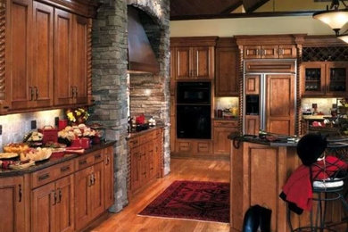 Inredning av ett rustikt avskilt, stort kök, med en undermonterad diskho, luckor med infälld panel, skåp i mellenmörkt trä, granitbänkskiva, grått stänkskydd, stänkskydd i stenkakel, svarta vitvaror, mellanmörkt trägolv och en köksö