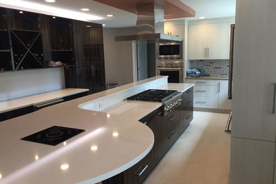 Example of a trendy l-shaped travertine floor enclosed kitchen design in Boston with flat-panel cabinets, dark wood cabinets, quartzite countertops, multicolored backsplash, matchstick tile backsplash, stainless steel appliances and an island