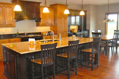 Example of a mid-sized classic l-shaped medium tone wood floor eat-in kitchen design in Other with an undermount sink, raised-panel cabinets, medium tone wood cabinets, granite countertops, stainless steel appliances and an island
