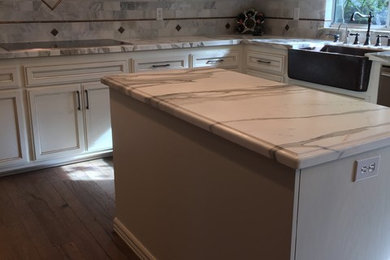 Inspiration for a large craftsman u-shaped medium tone wood floor and brown floor eat-in kitchen remodel in Sacramento with white cabinets, marble countertops, gray backsplash, stone tile backsplash, an island, a farmhouse sink and recessed-panel cabinets