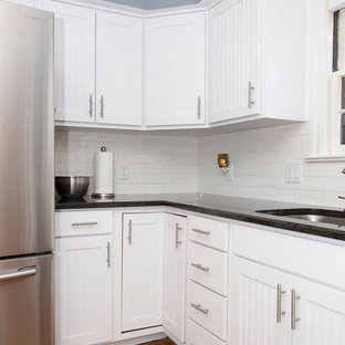 Design ideas for a mid-sized contemporary l-shaped eat-in kitchen in Other with a double-bowl sink, white cabinets, granite benchtops, white splashback, stainless steel appliances, with island, louvered cabinets, subway tile splashback, medium hardwood floors, brown floor and black benchtop.