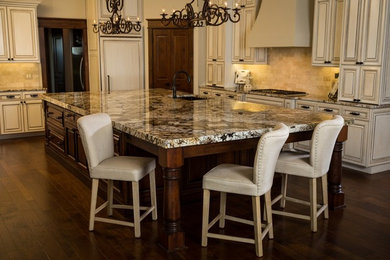 Inspiration for a large timeless l-shaped dark wood floor open concept kitchen remodel in Austin with an undermount sink, raised-panel cabinets, white cabinets, granite countertops, beige backsplash, stone tile backsplash, paneled appliances and an island