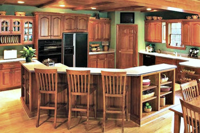 Inspiration for a craftsman light wood floor and beige floor kitchen remodel in Phoenix with raised-panel cabinets, medium tone wood cabinets, granite countertops, black appliances and an island