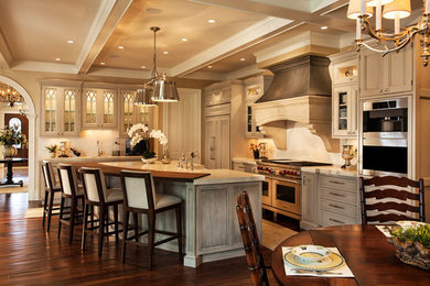 Example of a large transitional l-shaped dark wood floor and brown floor eat-in kitchen design in San Diego with stainless steel appliances, beige backsplash, mosaic tile backsplash, a farmhouse sink, recessed-panel cabinets, beige cabinets, granite countertops and an island