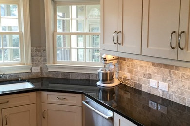 Example of a mid-sized transitional u-shaped medium tone wood floor enclosed kitchen design in Charlotte with an undermount sink, shaker cabinets, white cabinets, solid surface countertops, multicolored backsplash, stone tile backsplash, stainless steel appliances and an island