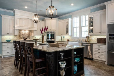 Inspiration for a large timeless l-shaped ceramic tile and brown floor eat-in kitchen remodel in New Orleans with a farmhouse sink, raised-panel cabinets, white cabinets, granite countertops, beige backsplash, ceramic backsplash, stainless steel appliances and an island