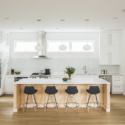 Example of a mid-sized danish l-shaped light wood floor eat-in kitchen design in Little Rock with an undermount sink, flat-panel cabinets, white cabinets, quartz countertops, white backsplash, glass tile backsplash, stainless steel appliances and an island