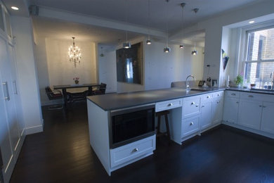 Example of a large classic l-shaped dark wood floor kitchen design in New York with white cabinets and a peninsula