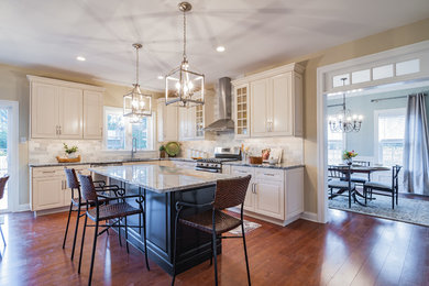 Enclosed kitchen - mid-sized transitional l-shaped medium tone wood floor and brown floor enclosed kitchen idea in Philadelphia with an undermount sink, raised-panel cabinets, white cabinets, gray backsplash, stone tile backsplash, stainless steel appliances and an island