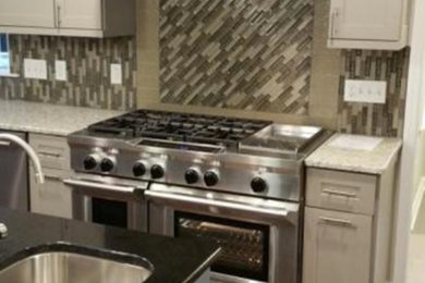 Inspiration for a contemporary medium tone wood floor and brown floor kitchen remodel in Charlotte with an undermount sink, shaker cabinets, granite countertops, multicolored backsplash, matchstick tile backsplash, stainless steel appliances, an island and gray cabinets
