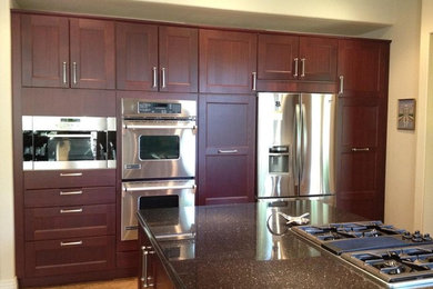 Example of a mid-sized transitional single-wall medium tone wood floor and beige floor enclosed kitchen design in Denver with a double-bowl sink, terrazzo countertops, beige backsplash, subway tile backsplash, stainless steel appliances, an island, recessed-panel cabinets and dark wood cabinets