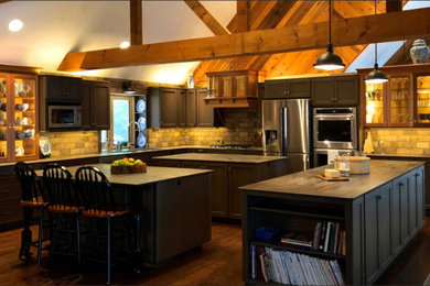 Eat-in kitchen - large rustic u-shaped dark wood floor and brown floor eat-in kitchen idea in Boston with an undermount sink, recessed-panel cabinets, gray cabinets, soapstone countertops, beige backsplash, travertine backsplash, stainless steel appliances, two islands and black countertops
