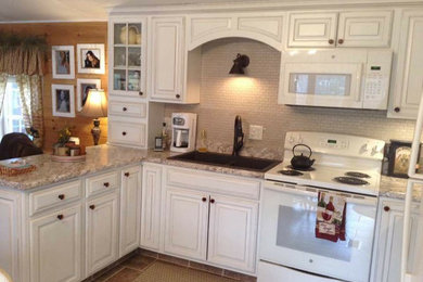 Inspiration for a mid-sized timeless u-shaped ceramic tile and brown floor open concept kitchen remodel in Portland Maine with a double-bowl sink, raised-panel cabinets, white cabinets, laminate countertops, beige backsplash, ceramic backsplash, white appliances and a peninsula