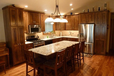 Example of a mid-sized transitional l-shaped medium tone wood floor eat-in kitchen design in Philadelphia with an undermount sink, raised-panel cabinets, medium tone wood cabinets, granite countertops, stainless steel appliances and an island