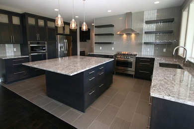 Open concept kitchen - large modern u-shaped porcelain tile and gray floor open concept kitchen idea in Phoenix with an undermount sink, flat-panel cabinets, dark wood cabinets, granite countertops, multicolored backsplash, stainless steel appliances, an island and glass tile backsplash