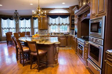 Inspiration for a mid-sized timeless u-shaped dark wood floor and brown floor eat-in kitchen remodel in Philadelphia with a double-bowl sink, recessed-panel cabinets, dark wood cabinets, granite countertops, metallic backsplash, glass tile backsplash, an island and stainless steel appliances