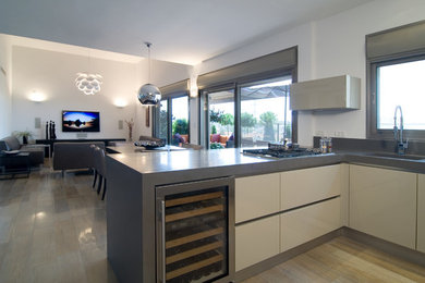 Foto på ett mellanstort funkis kök, med en integrerad diskho, släta luckor, vita skåp, bänkskiva i betong, rostfria vitvaror, ljust trägolv, en halv köksö och brunt golv