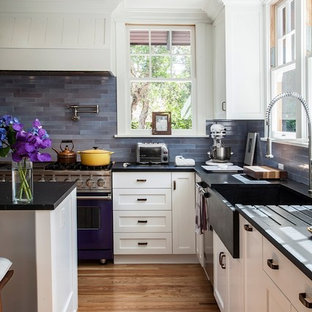 Photo of a traditional l-shaped kitchen in Los Angeles with a farmhouse sink, shaker cabinets, white cabinets, blue splashback, coloured appliances and slate splashback.