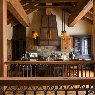This is an example of a large country galley open plan kitchen in Sacramento with raised-panel cabinets, medium wood cabinets, wood benchtops, multi-coloured splashback, slate splashback, panelled appliances, medium hardwood floors, with island and brown floor.
