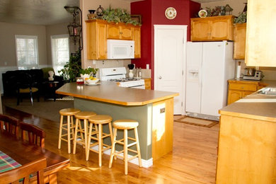 Küche mit hellbraunen Holzschränken, Laminat-Arbeitsplatte, braunem Holzboden und Halbinsel in Boise