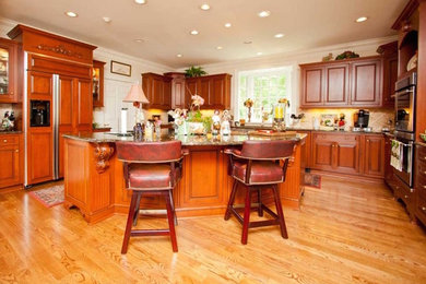 Open concept kitchen - mid-sized traditional l-shaped medium tone wood floor and beige floor open concept kitchen idea in Raleigh with an undermount sink, raised-panel cabinets, dark wood cabinets, quartz countertops, beige backsplash, ceramic backsplash, stainless steel appliances and an island