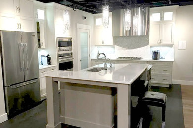Trendy kitchen photo in Calgary with an undermount sink, shaker cabinets, white cabinets, white backsplash, stainless steel appliances and an island