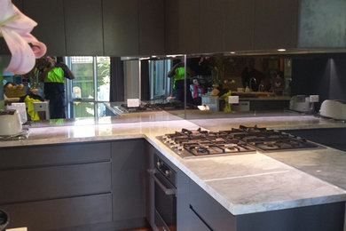 Kleine Moderne Wohnküche in L-Form mit Unterbauwaschbecken, grauen Schränken, Marmor-Arbeitsplatte, Rückwand aus Spiegelfliesen, Küchengeräten aus Edelstahl, Küchenrückwand in Grau und Kücheninsel in Melbourne