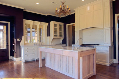 Klassische Küche mit weißen Schränken, Küchenrückwand in Weiß und braunem Holzboden in Sonstige