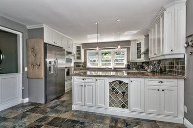 Bild på ett stort vintage kök, med luckor med infälld panel, vita skåp, granitbänkskiva, flerfärgad stänkskydd, rostfria vitvaror och en halv köksö