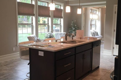 Example of a mid-sized transitional l-shaped ceramic tile eat-in kitchen design in Boston with a double-bowl sink, recessed-panel cabinets, dark wood cabinets, solid surface countertops, stainless steel appliances and an island