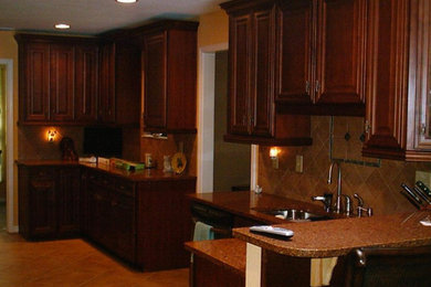 Inspiration for a mid-sized timeless u-shaped kitchen remodel in Jacksonville with an undermount sink, raised-panel cabinets, dark wood cabinets, granite countertops, beige backsplash and stainless steel appliances