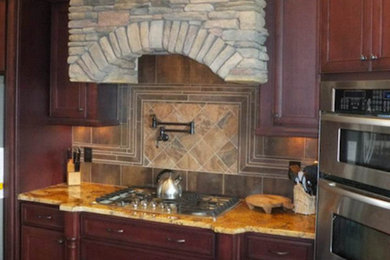 Cette photo montre une grande cuisine américaine en L et bois foncé avec plan de travail en marbre, une crédence beige, une crédence en céramique, un électroménager en acier inoxydable, un sol en bois brun et îlot.