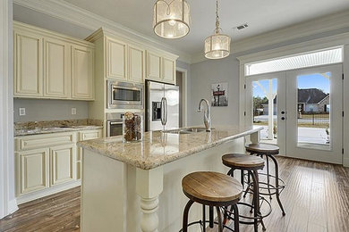 Photo of a medium sized traditional kitchen in New Orleans with a built-in sink, beaded cabinets, white cabinets, beige splashback, stainless steel appliances and an island.
