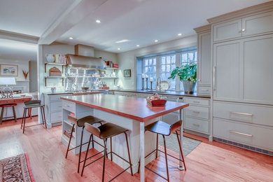 Photo of a large farmhouse l-shaped enclosed kitchen in Philadelphia with a submerged sink, shaker cabinets, white cabinets, concrete worktops, integrated appliances, medium hardwood flooring, an island, brown floors and grey worktops.