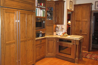 Diseño de cocina lineal tradicional de tamaño medio con puertas de armario de madera oscura, suelo de madera en tonos medios y península