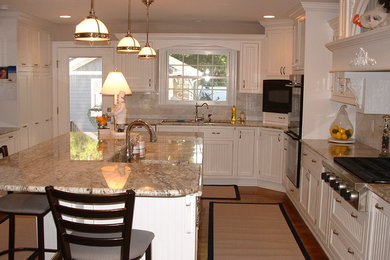 Kitchen - large traditional l-shaped medium tone wood floor and brown floor kitchen idea in Baltimore with an island, shaker cabinets, white cabinets, granite countertops, beige backsplash and black appliances