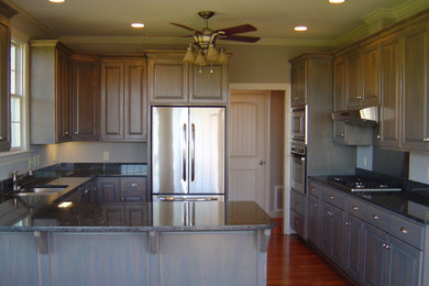 Bild på ett avskilt, stort rustikt u-kök, med en undermonterad diskho, luckor med upphöjd panel, skåp i mellenmörkt trä, granitbänkskiva, rostfria vitvaror, mörkt trägolv och en köksö