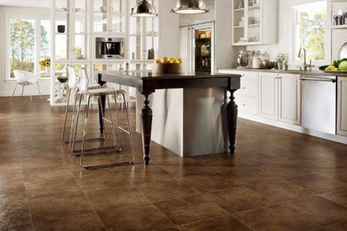 Imagen de cocina comedor lineal clásica con puertas de armario blancas, suelo laminado, una isla y suelo marrón
