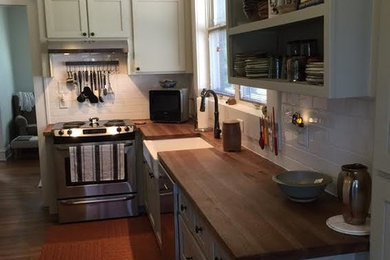 Inspiration for a mid-sized timeless l-shaped dark wood floor enclosed kitchen remodel in Atlanta with a farmhouse sink, shaker cabinets, gray cabinets, wood countertops, white backsplash, subway tile backsplash, stainless steel appliances and no island