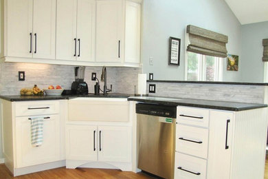 Enclosed kitchen - mid-sized cottage l-shaped medium tone wood floor and brown floor enclosed kitchen idea in Philadelphia with a farmhouse sink, shaker cabinets, white cabinets, quartz countertops, gray backsplash, marble backsplash, stainless steel appliances and a peninsula