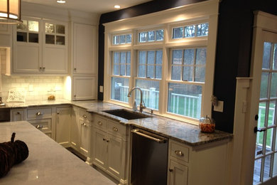 Eat-in kitchen - contemporary l-shaped eat-in kitchen idea in Boston with a single-bowl sink, shaker cabinets, white cabinets, granite countertops, white backsplash, stone tile backsplash, stainless steel appliances and an island