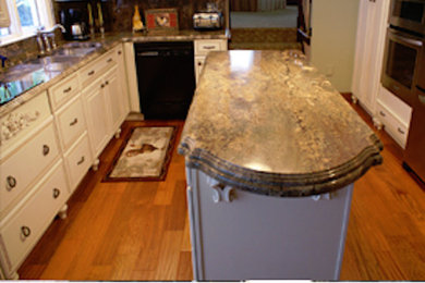 Example of a mid-sized l-shaped medium tone wood floor enclosed kitchen design in New York with a double-bowl sink, white cabinets, granite countertops, stainless steel appliances and an island