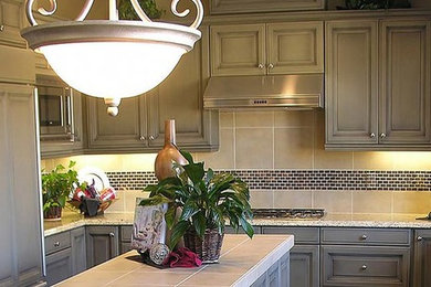 Inspiration for a mid-sized timeless u-shaped eat-in kitchen remodel in St Louis with a double-bowl sink, green cabinets, tile countertops, gray backsplash, glass tile backsplash, stainless steel appliances and an island