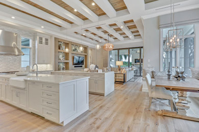 Huge elegant l-shaped light wood floor and brown floor open concept kitchen photo in Miami with a farmhouse sink, shaker cabinets, white cabinets, granite countertops, gray backsplash, matchstick tile backsplash, two islands and gray countertops