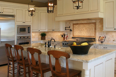 Large country l-shaped brown floor kitchen photo in Phoenix with a farmhouse sink, beaded inset cabinets, beige cabinets, granite countertops, brown backsplash, travertine backsplash, stainless steel appliances, an island and beige countertops