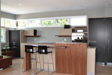 Example of a mid-sized trendy galley light wood floor open concept kitchen design in Ottawa with an undermount sink, flat-panel cabinets, beige cabinets, quartzite countertops, paneled appliances and an island