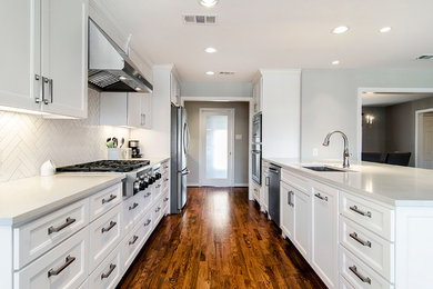 Example of a transitional u-shaped eat-in kitchen design in Dallas with an undermount sink, flat-panel cabinets, white cabinets, granite countertops, porcelain backsplash, stainless steel appliances and white backsplash