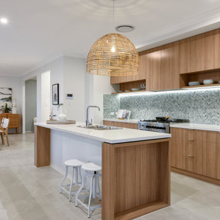 This is an example of a contemporary galley kitchen in Brisbane with a drop-in sink, flat-panel cabinets, medium wood cabinets, blue splashback, mosaic tile splashback, stainless steel appliances, with island, grey floor and white benchtop.